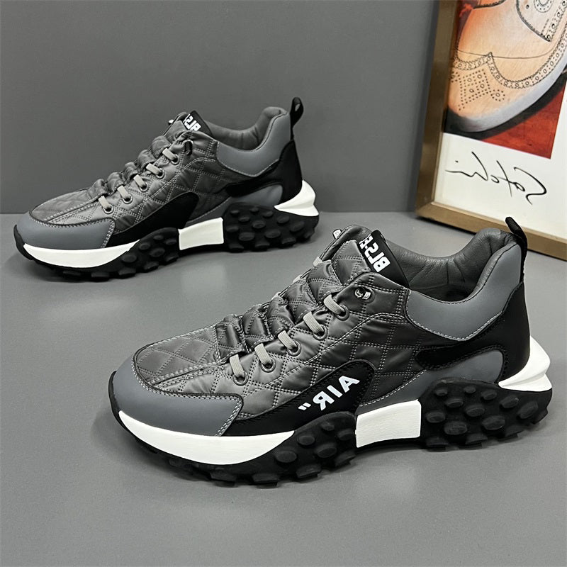 Afbeelding van de HerlevenX sneakers in een stijlvolle grijze uitvoering met zwarte en witte accenten. Deze dynamische en comfortabele schoenen hebben een unieke zool met noppenprofiel voor optimale grip en stabiliteit. Het ademende, gewatteerde bovenwerk zorgt voor langdurig draagcomfort en een moderne uitstraling. Perfect voor sportieve en casual gelegenheden, met een trendy en eigentijdse look.