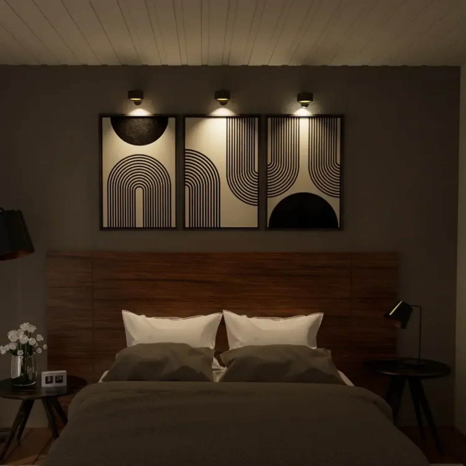 Sfeervolle slaapkamer verlicht door Aurora Glow draadloze wandlampen. De minimalistische zwarte lampen accentueren de wanddecoratie met een warme, gerichte lichtbundel, wat zorgt voor een elegante en moderne ambiance. Perfect voor functionele en decoratieve verlichting in elke slaapkamer.