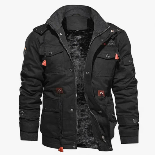 Afbeelding van het Bamox bomberjack in zwart. Het jack heeft een stoere uitstraling met meerdere zakken, knopen en ritssluitingen. De opvallende oranje accenten op de ritstrekkers en knopen geven het een trendy look. De binnenkant is gevoerd met zacht en warm materiaal, ideaal voor koude dagen. De hoge kraag en verstelbare manchetten bieden extra bescherming tegen wind en kou.