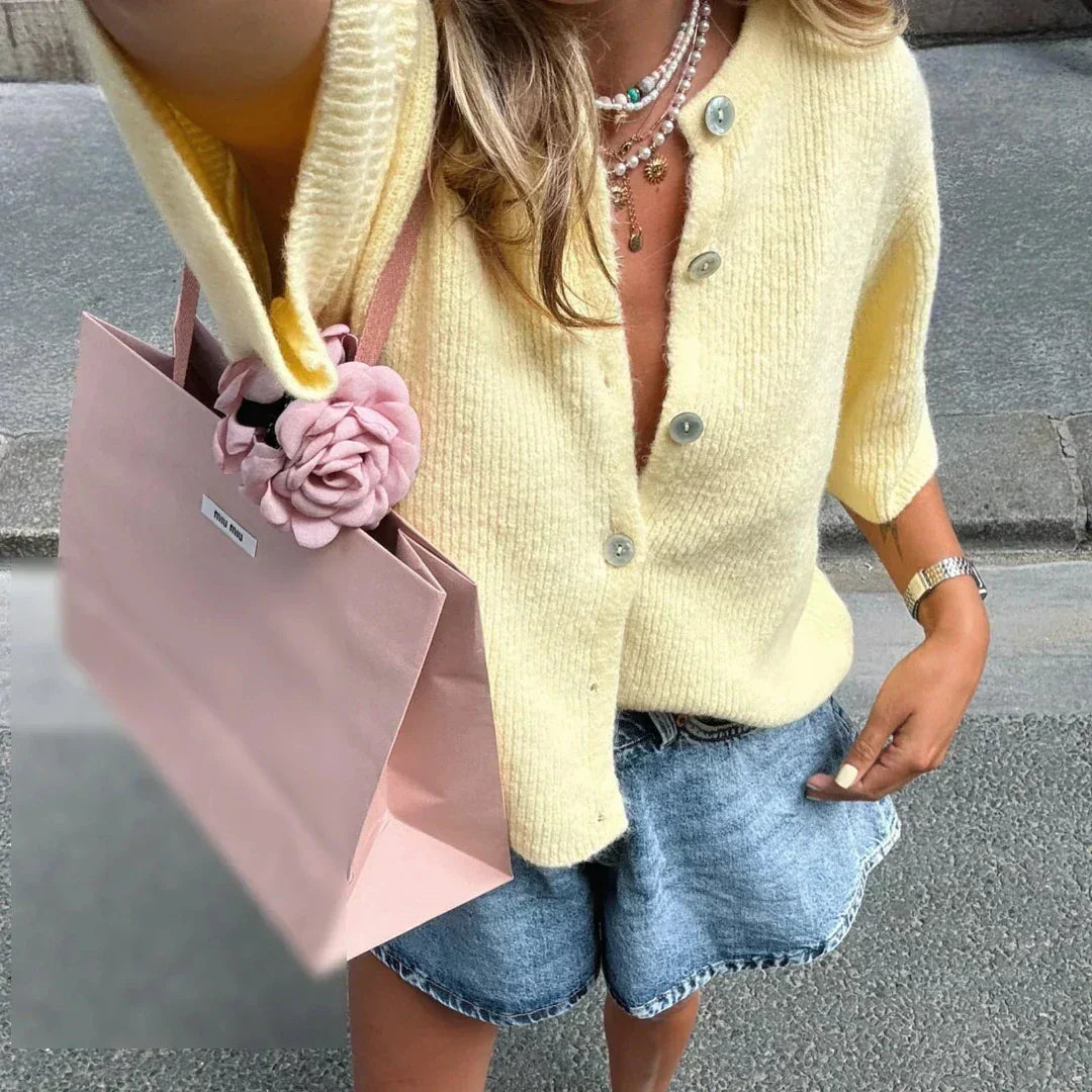 Bellorra vrouwelijk gilet in zachtgeel, met korte mouwen en een tijdloze uitstraling. Het gilet heeft een klassieke knoopsluiting en wordt moeiteloos gecombineerd met denim shorts voor een frisse zomerse look. Perfect voor casual dagen of een stijlvolle wandeling door de stad.