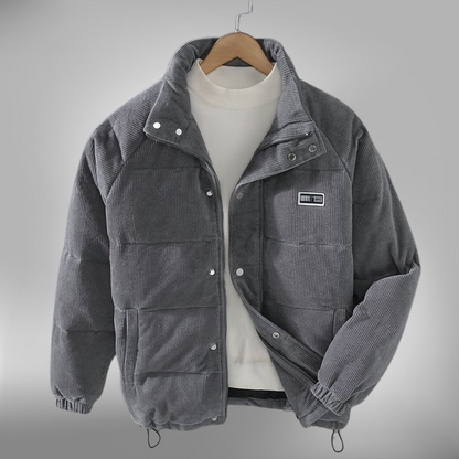 De Borealis winterjas in grijs corduroy biedt zowel warmte als stijl. Het heeft een comfortabele, gewatteerde pasvorm en een praktische ritssluiting met drukknopen. De jas is ideaal voor de koude wintermaanden, met een casual ontwerp en een subtiele merkpatch op de borst. Perfect voor dagelijks gebruik, biedt deze jas zowel bescherming tegen de kou als een modieuze uitstraling.