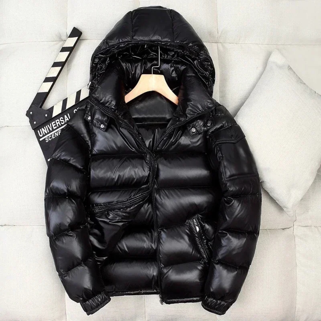 Borstin Winterjas Puffer in glanzend zwart. Deze stijlvolle gewatteerde winterjas met capuchon biedt ultieme warmte en comfort voor koude dagen. Perfect voor heren met een moderne uitstraling.