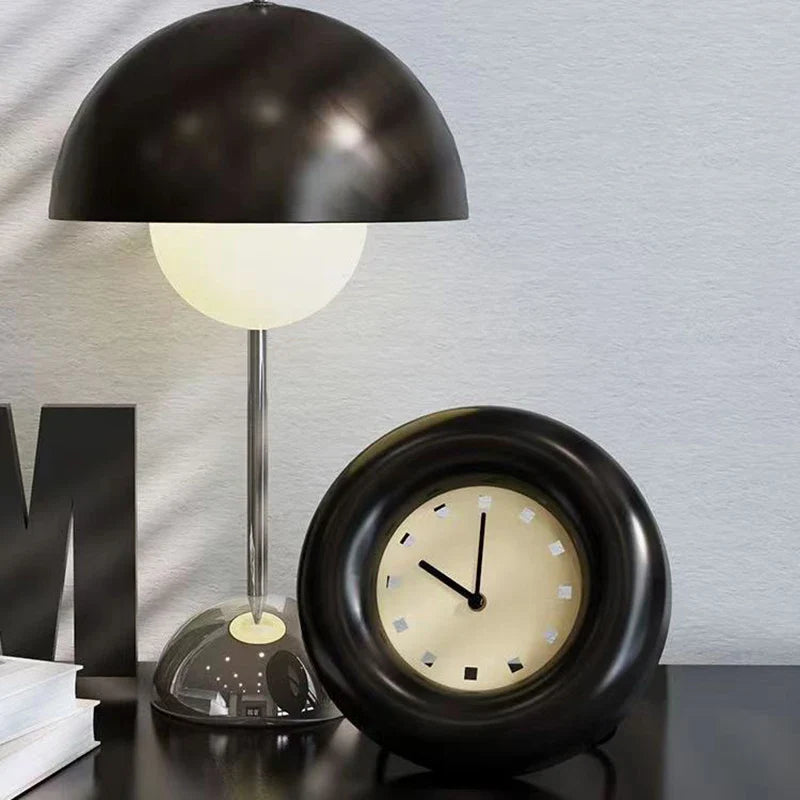 Elekta alarmklok met een strak ontwerp, gecombineerd met een moderne bureaulamp. Het klokje heeft een eenvoudig, elegant zwart ontwerp met een wijzerplaat in zachte kleuren, perfect voor een stijlvolle uitstraling.