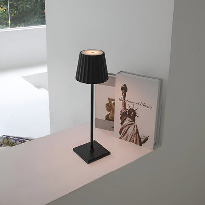 De Gellura LED-tafellamp met een strak zwart ontwerp en een plooien lampenkap voegt een moderne, aanpasbare verlichting toe aan elk interieur. Het minimalistische ontwerp staat op een vierkante basis en biedt een elegante uitstraling, ideaal voor zowel functionele als decoratieve doeleinden.