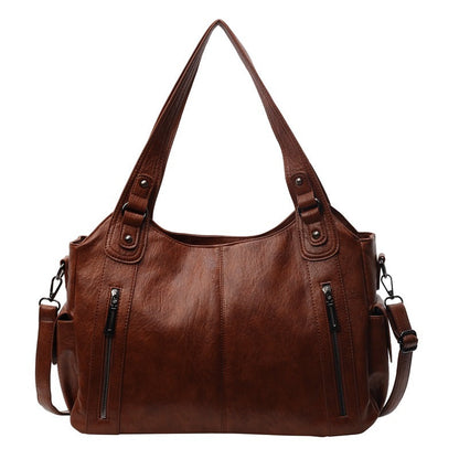 Kaldar stijlvolle leren tas in Koffie, met een elegant design en dubbele handvatten. De tas heeft voorvakken met ritssluitingen en een afneembare schouderriem, wat zorgt voor veelzijdigheid en praktische opbergruimte. Perfect voor dagelijks gebruik met een tijdloze uitstraling.