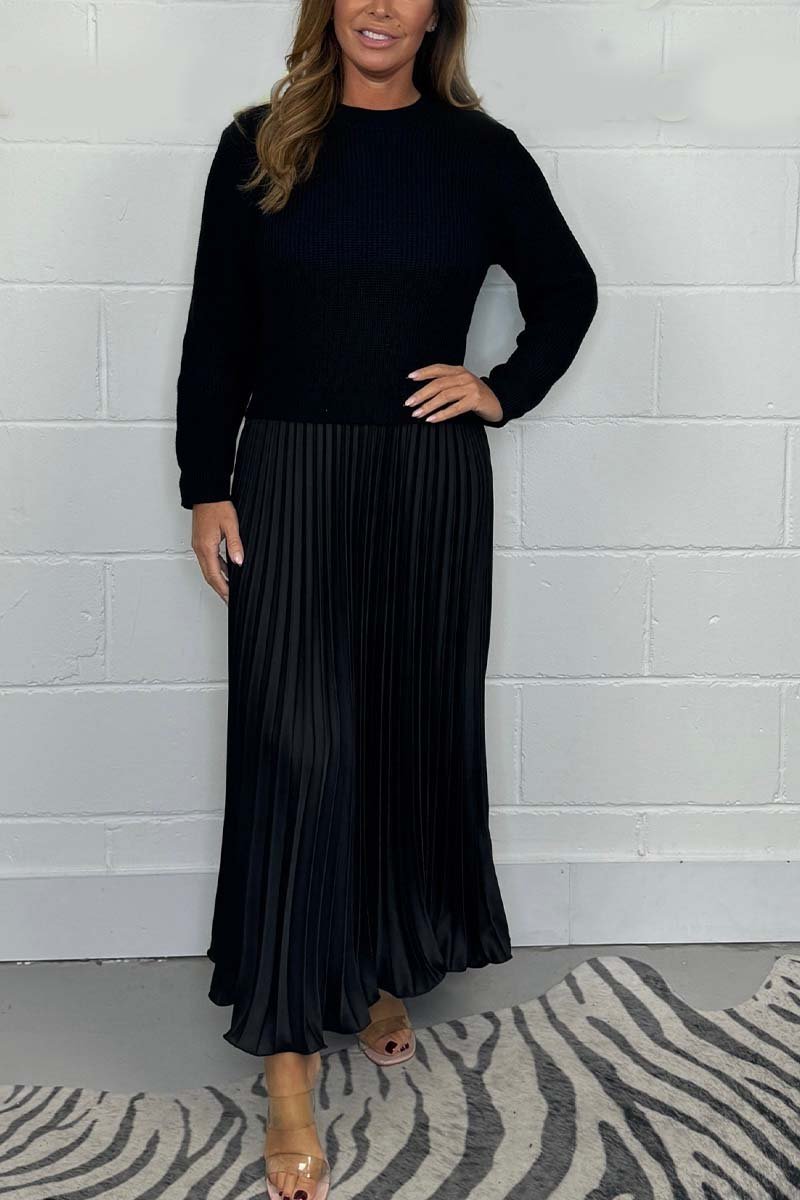 Een tijdloze pleated jurk van Kendra, met een zwarte trui-top en een elegante plissé rok in zwart. Deze verfijnde jurk biedt een stijlvolle uitstraling, perfect voor zowel formele als casual gelegenheden.