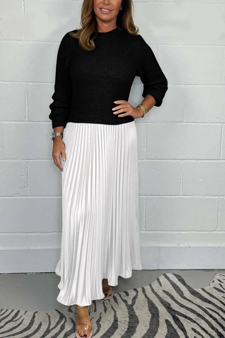 Een elegante, tijdloze plissé jurk van Kendra in wit, gecombineerd met een zwart, gebreid bovenstuk. Deze verfijnde look is perfect voor zowel casual als chique gelegenheden.