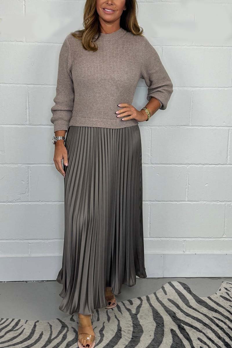 Een stijlvolle tijdloze pleated jurk van Kendra, met een beige trui-top en een elegante, plissé rok in een subtiele grijstint. De jurk biedt een verfijnde uitstraling en is perfect voor zowel casual als meer formele gelegenheden.