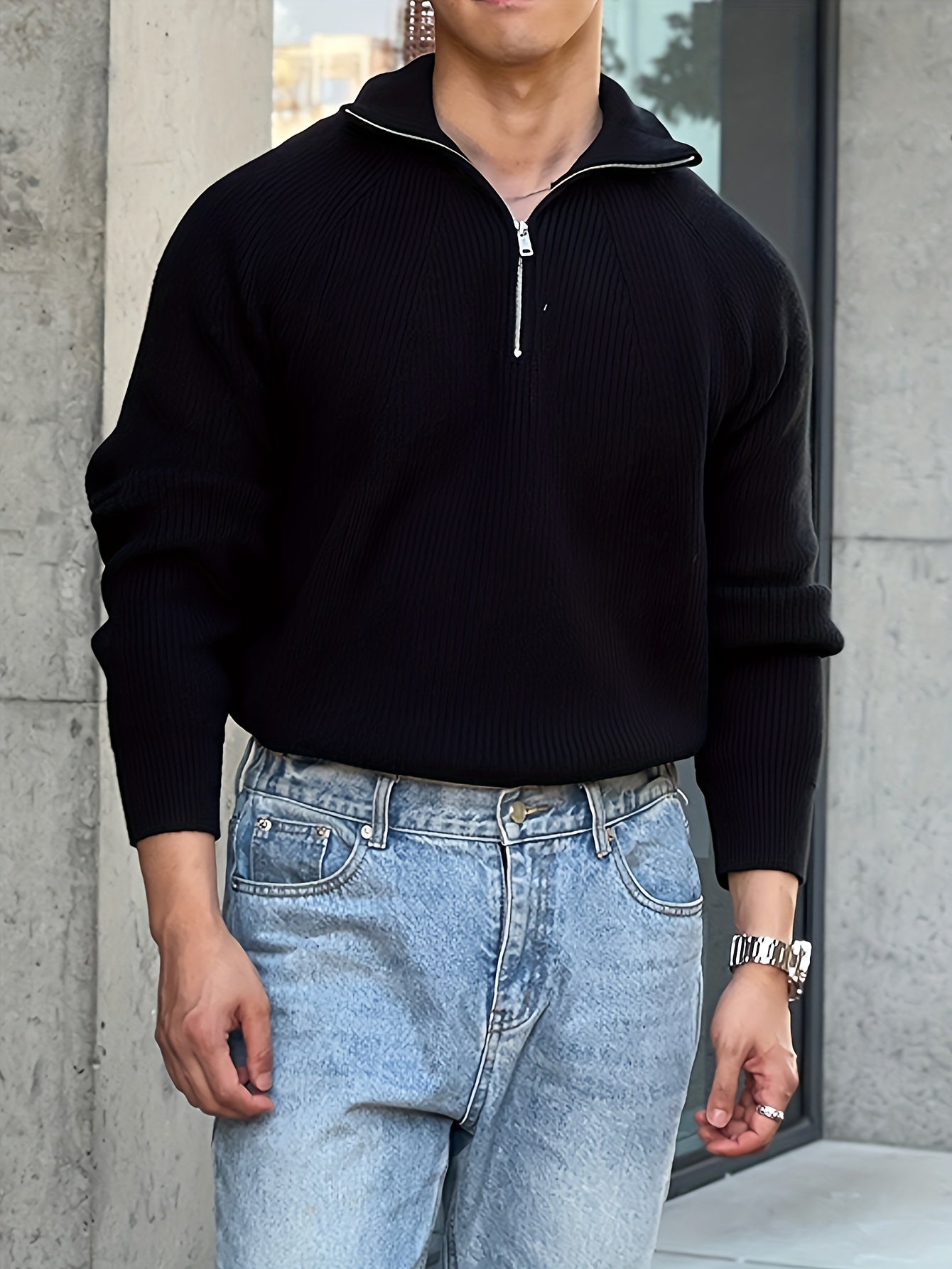 LIVANO heren trui in zwart, met een stijlvolle ritssluiting bij de hals. De trui heeft een geribbelde structuur en wordt gecombineerd met een casual look door de blauwe jeans.