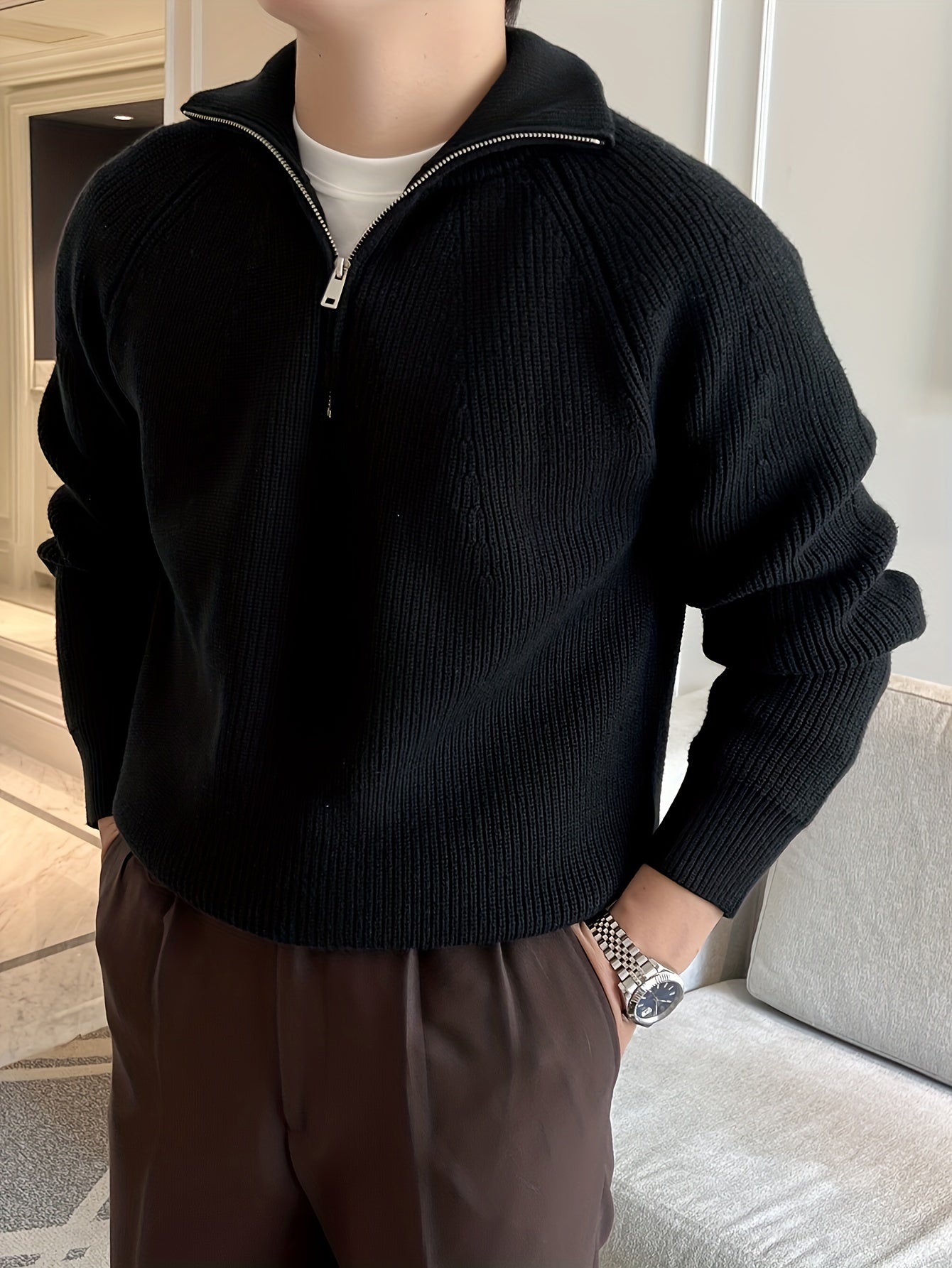 LIVANO heren trui in zwart met ritssluiting bij de hals, gecombineerd met een wit T-shirt en een bruine broek. De trui heeft een geribbelde structuur en biedt een stijlvolle en comfortabele uitstraling.