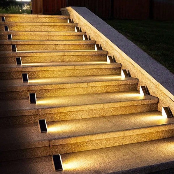 Een set trapverlichting van LumaGlow die de treden elegant verlicht, wat zorgt voor zowel veiligheid als stijl. De warme gloed van de verlichting accentueert het granieten oppervlak van de trap, waardoor een moderne en uitnodigende sfeer ontstaat. Perfect voor elke buiten- of binnentrap.
