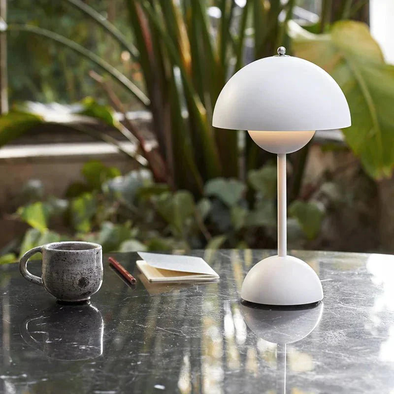 Elegant ontworpen LumiNova tafellamp met LED-verlichting, geplaatst op een moderne tafel in een groene, natuurlijke omgeving, perfect voor sfeervolle en functionele verlichting.