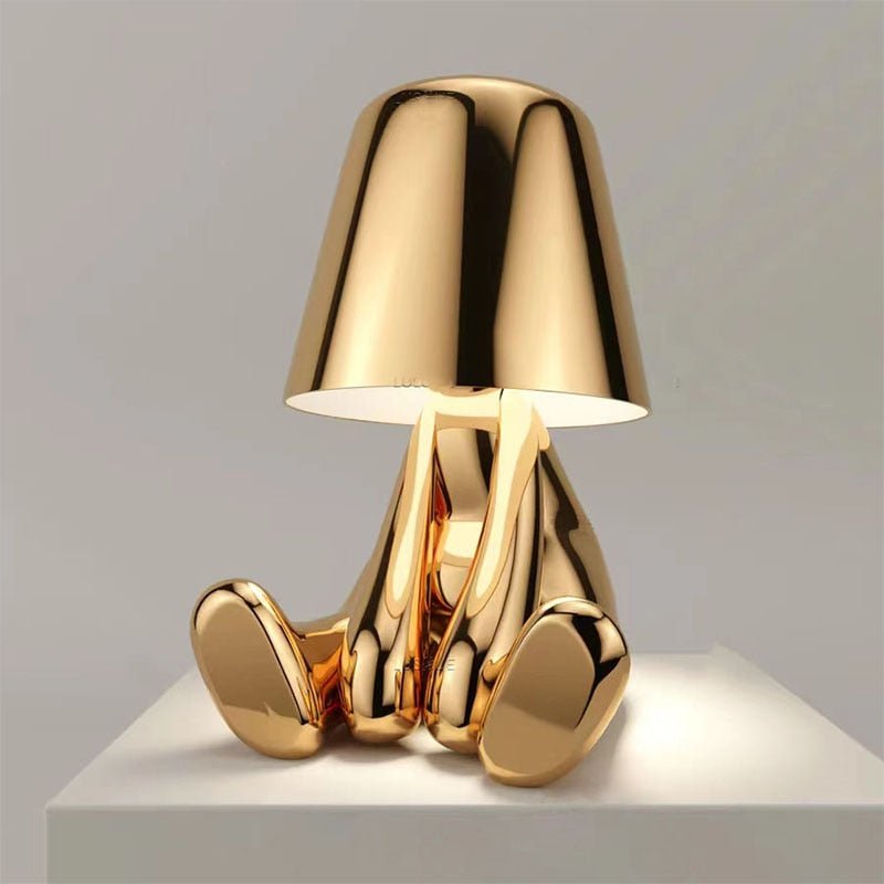 Glanzende gouden Lumineer tafellamp in speels en modern design, ideaal voor flexibele verlichting in stijlvolle interieurs.