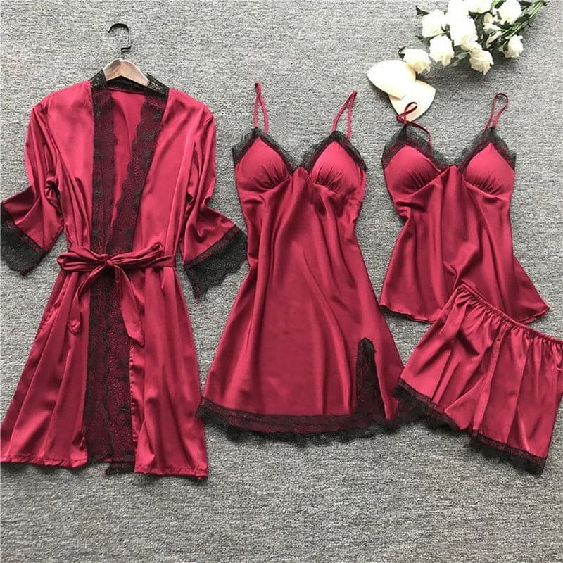 De afbeelding toont het LunaComfort pajamapakket in een elegante bordeauxrode kleur. Het pakket bevat een satijnen nachtjapon, chemise, nachthemd en een bijpassende short, allemaal versierd met verfijnde zwarte kant. Dit luxe setje biedt een ontspannende en verfijnde ervaring, perfect voor een comfortabele avond.