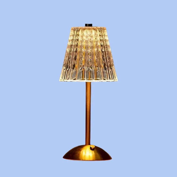 Een moderne draadloze tafellamp met een chique gouden voet en een kristalachtige geplooide lampenkap die een warme, uitnodigende gloed verspreidt. Het elegante ontwerp complementeert moderne interieurs en biedt zowel functionaliteit als stijl.