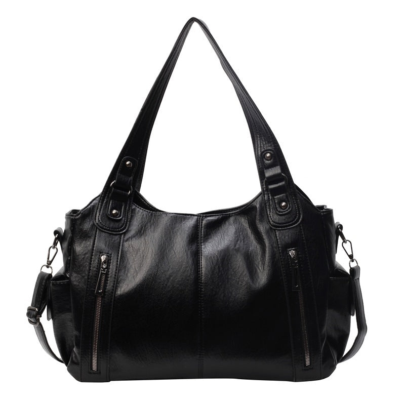 OLYNDA zwarte tote tas met twee ritsvakken aan de voorkant, stevige handgrepen en een schouderriem. Praktisch en tijdloos ontwerp.