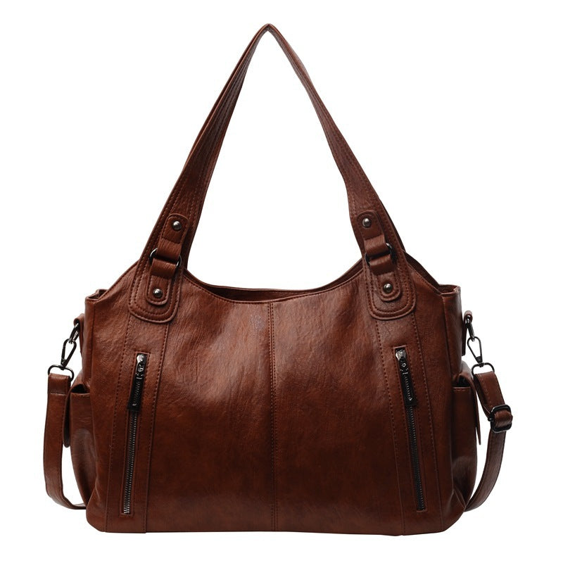 OLYNDA bruine leren tote tas met stijlvolle ritsdetails, perfect voor dagelijks gebruik met een praktisch en tijdloos ontwerp.