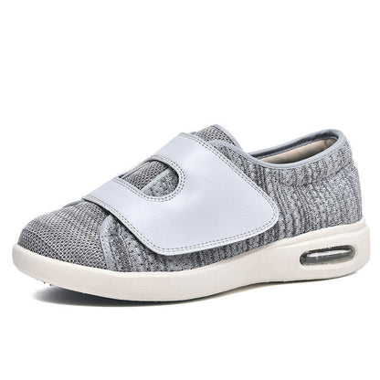 De afbeelding toont een comfortabele grijze schoen van Ondro, ontworpen met een brede pasvorm voor extra comfort. De schoen heeft een ademende bovenkant van stof en een klittenbandsluiting voor eenvoudige en snelle verstelling. De zool is uitgerust met luchtkussens voor demping, wat zorgt voor langdurig draagcomfort. Deze schoen is ideaal voor dagelijks gebruik.