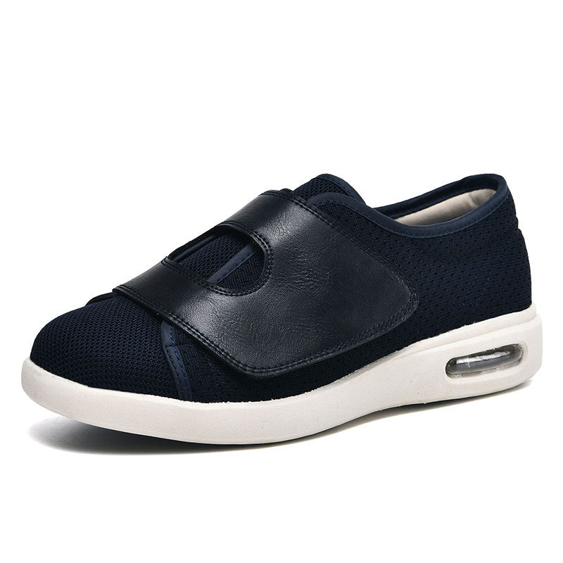 De afbeelding toont een donkerblauwe schoen van Ondro, ontworpen voor een brede pasvorm en ultiem comfort. De schoen heeft een ademende mesh bovenkant gecombineerd met een leren klittenbandstrip voor een veilige en gemakkelijke sluiting. De zool beschikt over luchtkussens voor extra demping, wat zorgt voor een comfortabele ervaring tijdens het lopen. Deze schoenen zijn zowel praktisch als stijlvol, ideaal voor dagelijks gebruik.