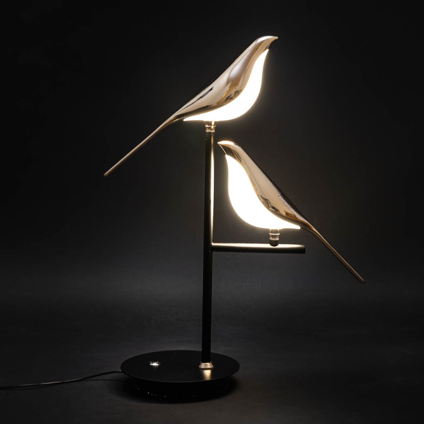 Sprankelum LED Tafellamp  Moderne verlichting met twee goudkleurige vogelontwerpen op een zwart metalen voet. De elegante vogels geven sfeervol licht, perfect voor het creëren van een verfijnde ambiance in elke ruimte.