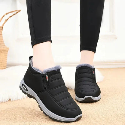 Zwarte Tessura schoenen met een zachte, warme voering rond de enkels, ontworpen voor comfort en warmte in de koude maanden. De schoenen hebben een sportieve uitstraling met een grijze zool en zijn ideaal voor dagelijks gebruik.