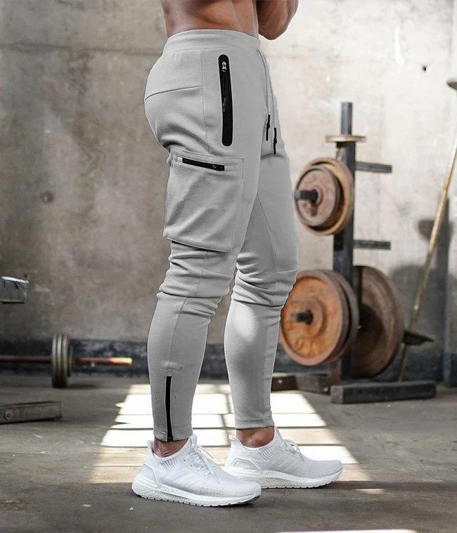 Afbeelding van de Umiro cargo jogger in lichtgrijs. Deze moderne jogger heeft een slim-fit pasvorm en is voorzien van meerdere stijlvolle zakken met ritssluiting, waaronder praktische cargozakken op de zijkant. De elastische tailleband biedt een comfortabele en verstelbare pasvorm, ideaal voor casual of sportieve activiteiten. Het zachte en flexibele materiaal zorgt voor optimaal draagcomfort.