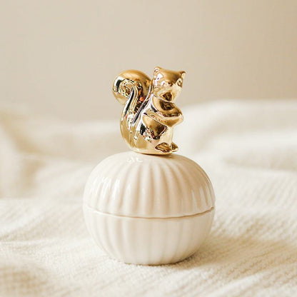 Een elegante opbergpot in de vorm van een schelp, met een gouden eekhoorn als deksel. Het verfijnde ontwerp van de eekhoorn en de pot voegt een speelse, maar chique uitstraling toe aan de opbergruimte.