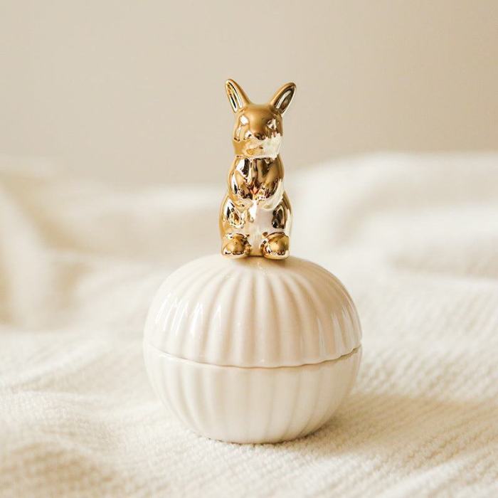 Een elegante opbergpot in de vorm van een schelp, met een gouden konijn als deksel. Het verfijnde ontwerp van het konijn en de pot geeft een speelse en chique uitstraling aan elke ruimte.