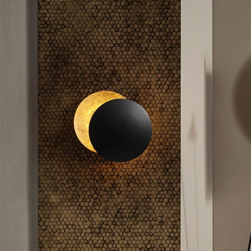 Wandlamp met zonsverduistering - Een stijlvolle en sfeervolle wandlamp met een uniek ontwerp dat een zonsverduistering nabootst. De zwarte ronde schijf blokkeert deels het warme gouden licht, wat een rustgevende en elegante uitstraling creëert. Perfect voor het toevoegen van een artistiek en modern element aan elke kamer