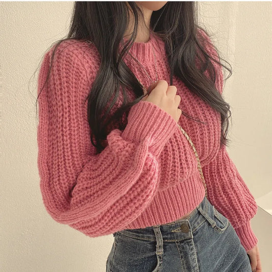Model draagt een roze gebreide trui van Yvano. De trui heeft een grove structuur, lange mouwen en een cropped design dat perfect combineert met een high-waisted jeans. De comfortabele pasvorm en warme uitstraling maken deze trui ideaal voor casual en trendy outfits. Yvano | Truien | Comfortabel.